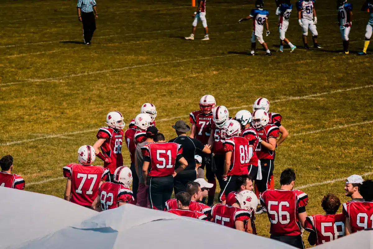 Un allenatore di football americano spiega tattica a una squadra di giocatori