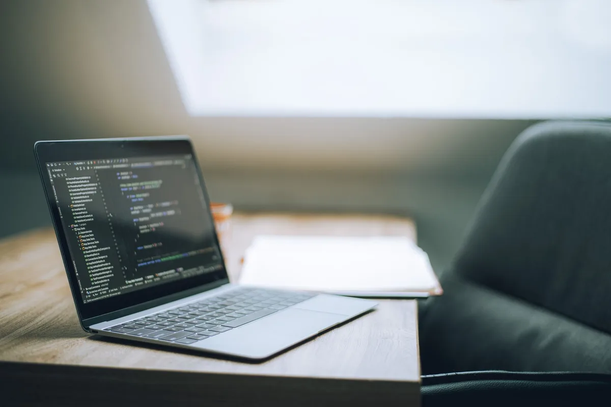 Sviluppatore al lavoro su un laptop con codice sullo schermo durante una sessione di programmazione