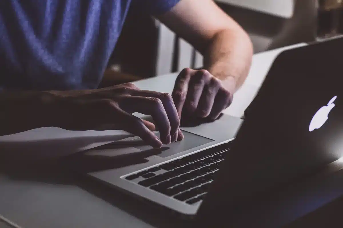 Mani che digitano velocemente su una tastiera con flussi di dati e metriche sullo schermo