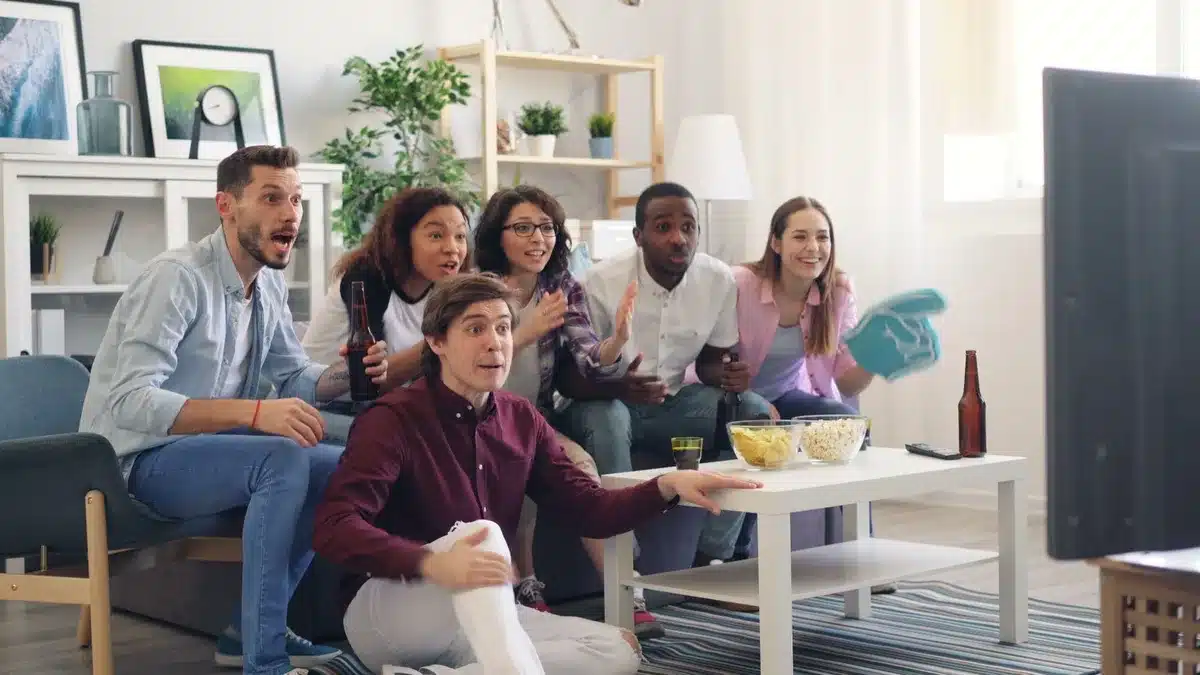 Persone riunite intorno a uno schermo che guardano una serie TV con entusiasmo