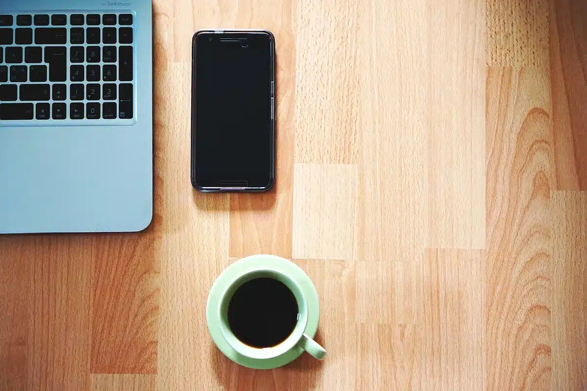 Mani che usano smartphone e portatile con schermate di posta e notifiche sfocate