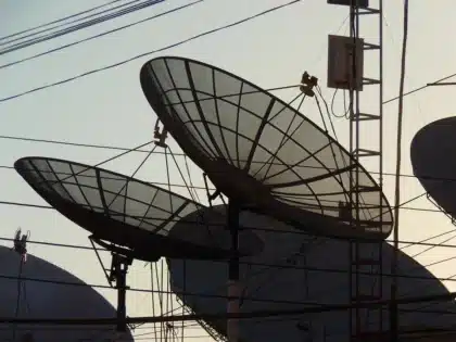 Antenne sul tetto e una mano che regola un cavo, luce del tramonto
