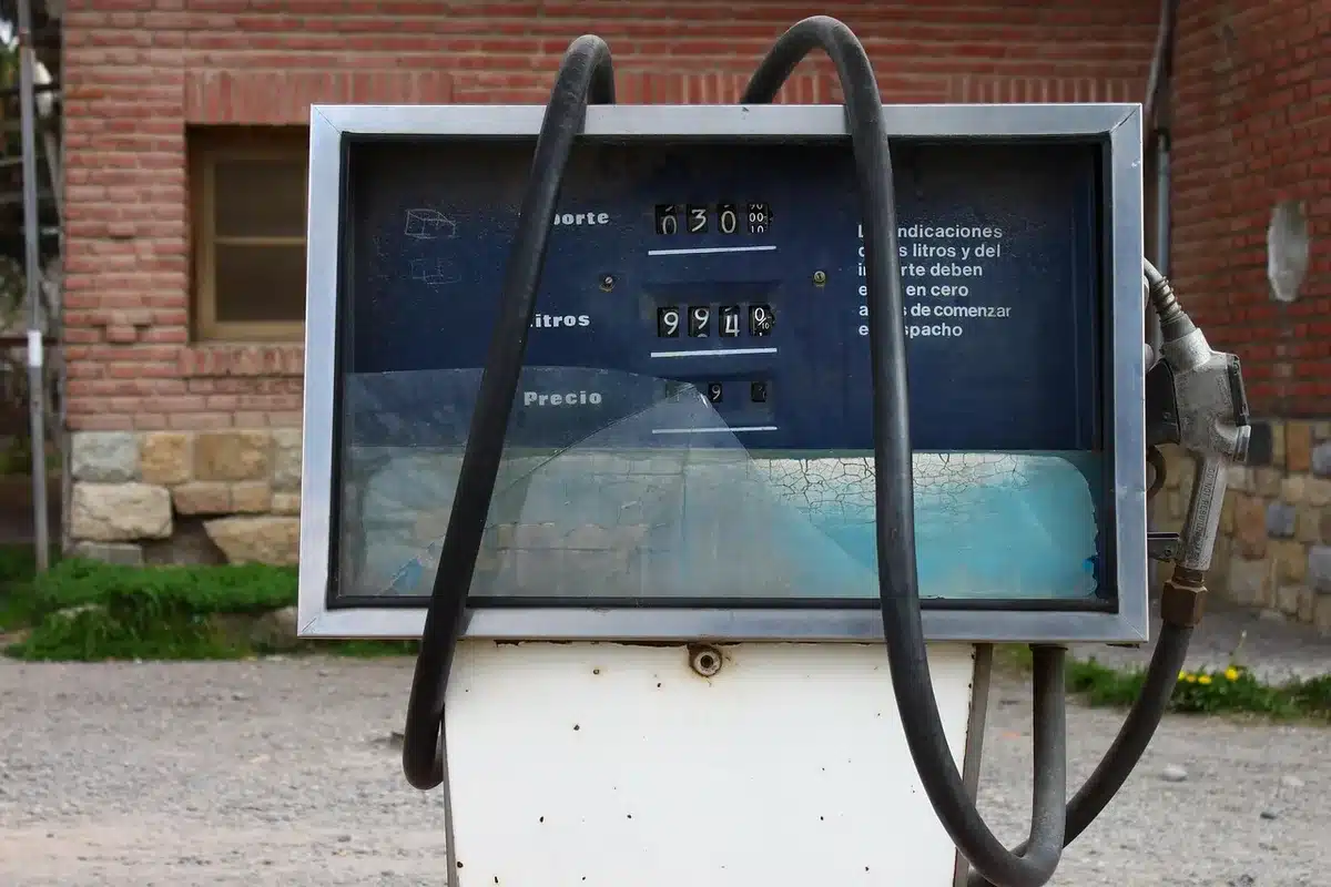 Pompa di carburante con display prezzi e auto in sosta