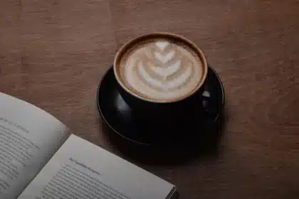 Mano anonima su un libro e appunti su un tavolo da caffè con un ciak sfocato