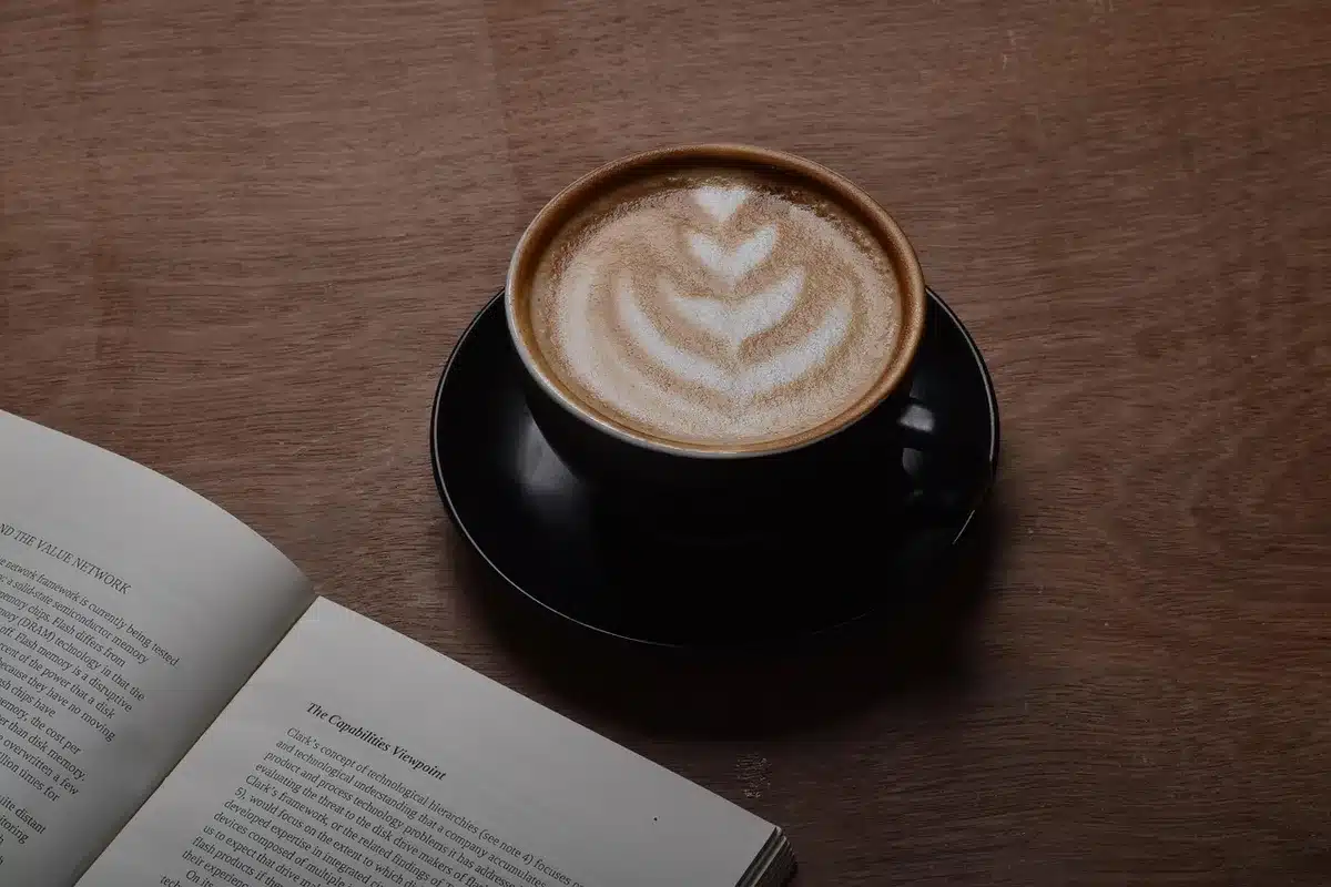Mano anonima su un libro e appunti su un tavolo da caffè con un ciak sfocato