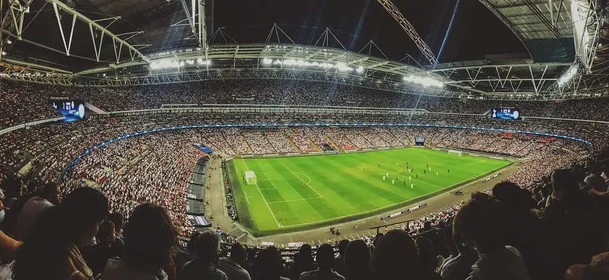 Veduta aerea di uno stadio gremito durante un concerto, con platee di migliaia di persone.