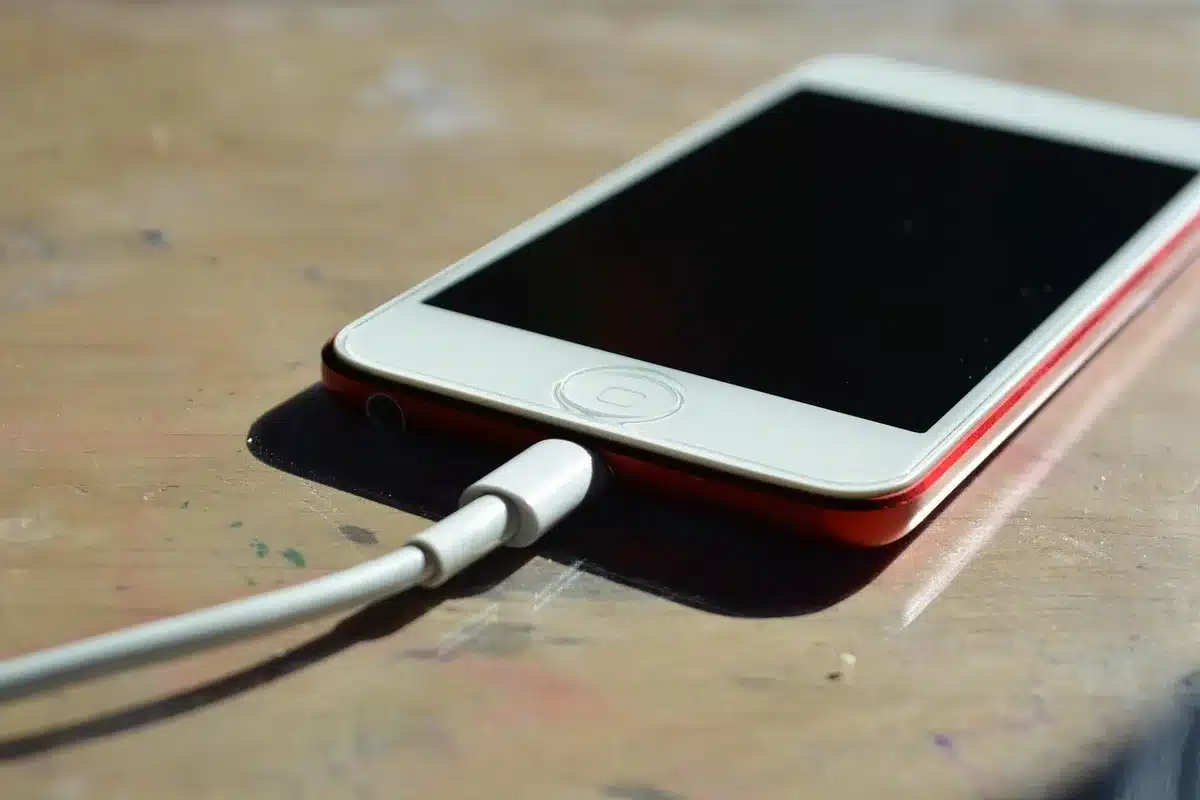 Smartphone in carica con cavo su tavolo, indicatore batteria visibile