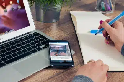 Mani anonime su laptop con player video sfocato e router sul tavolo