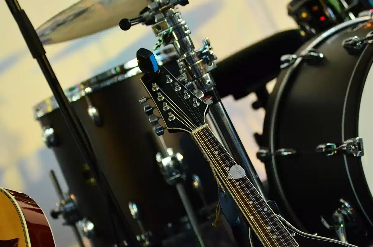 Bloc-notes con testi e chitarra in sala prove, simbolo del lavoro sui brani