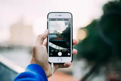 Mani anonime che tengono uno smartphone sopra una scrivania con cavi e schede, simulando pulizia memoria