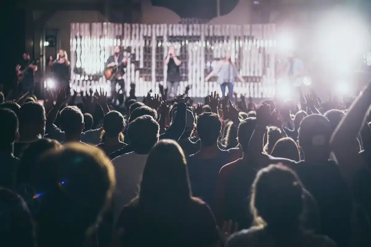 Folla davanti a un palco con luci vintage che richiama i concerti